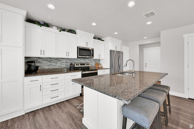 2777 West 4175th Street South, Unit 232 Roy, UT 84067 - Photo 10 of 27 Modern kitchen featuring white shaker cabinetry, granite countertops, stainless steel appliances, a tile backsplash, and LVP flooring