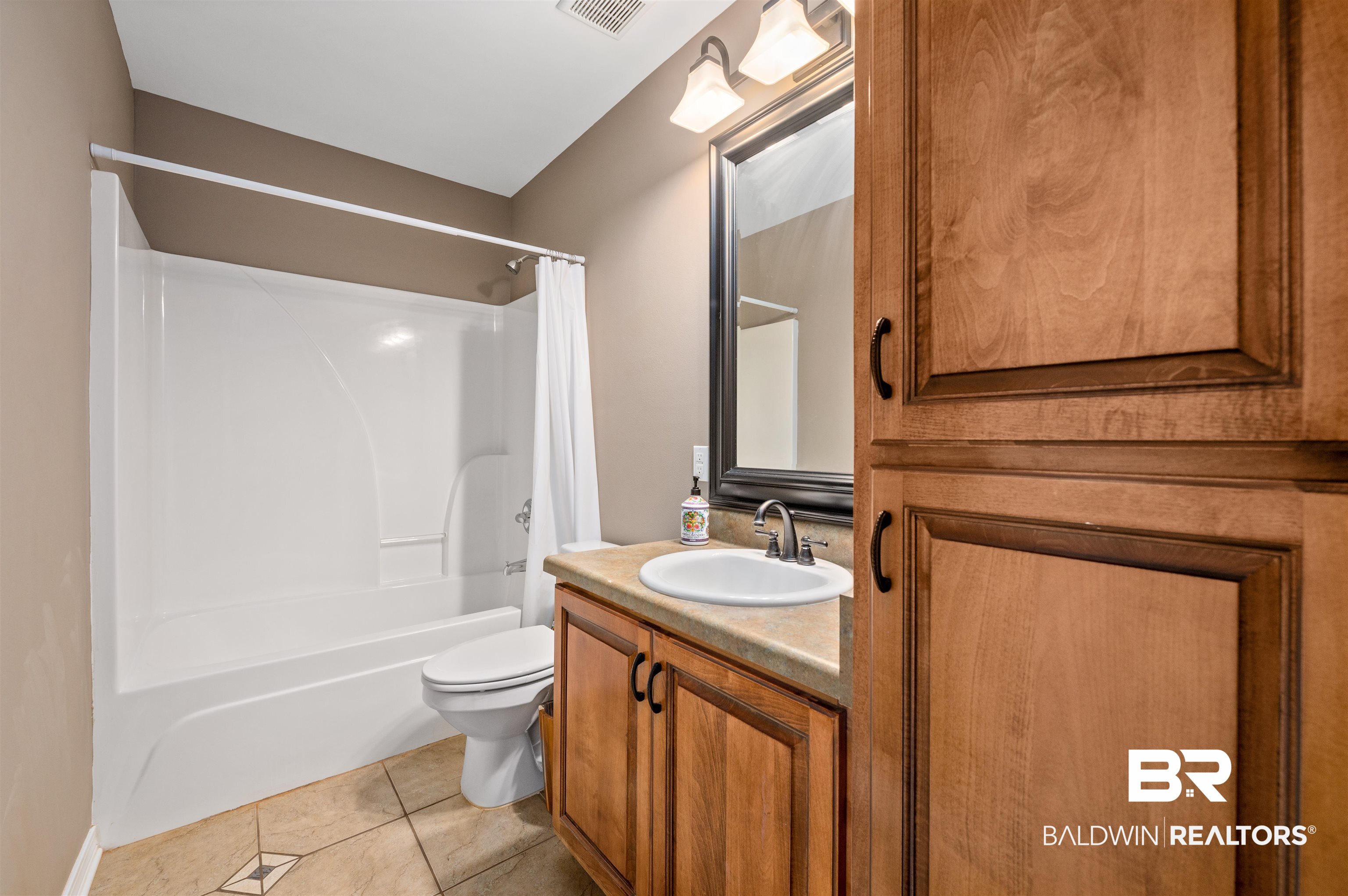 15240 Styx River Road Stapleton, AL 36578 - Photo 6 of 18 Full bathroom with shower / bath combination with curtain, vanity, toilet, and tile patterned floors