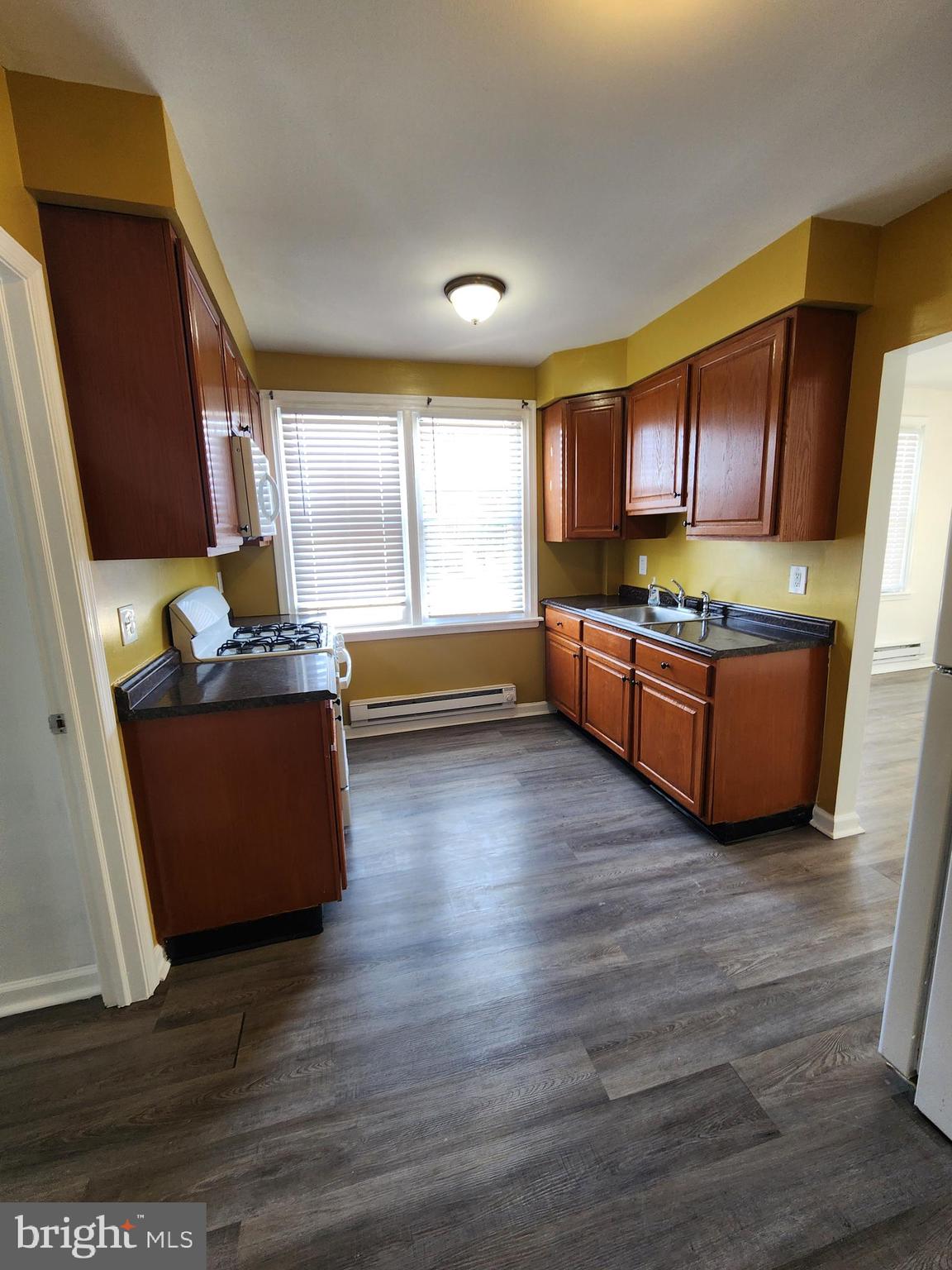 89 Sparks Street Philadelphia, PA 19120 - Photo 16 of 37 a kitchen with stainless steel appliances wooden floors and wooden cabinets