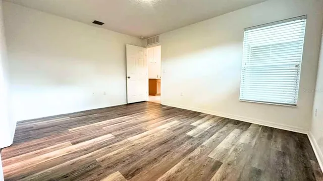 a view of empty room with wooden floor and fan