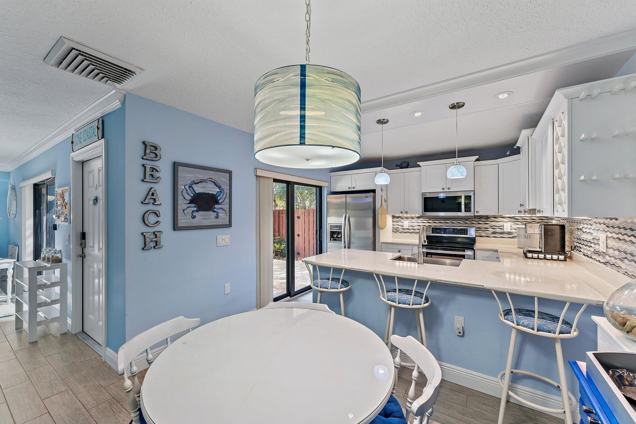 2403 24th Court Jupiter, FL 33477 - Photo 11 of 29 a kitchen with stainless steel appliances a stove a refrigerator a sink dishwasher a dining table and chairs with wooden floor
