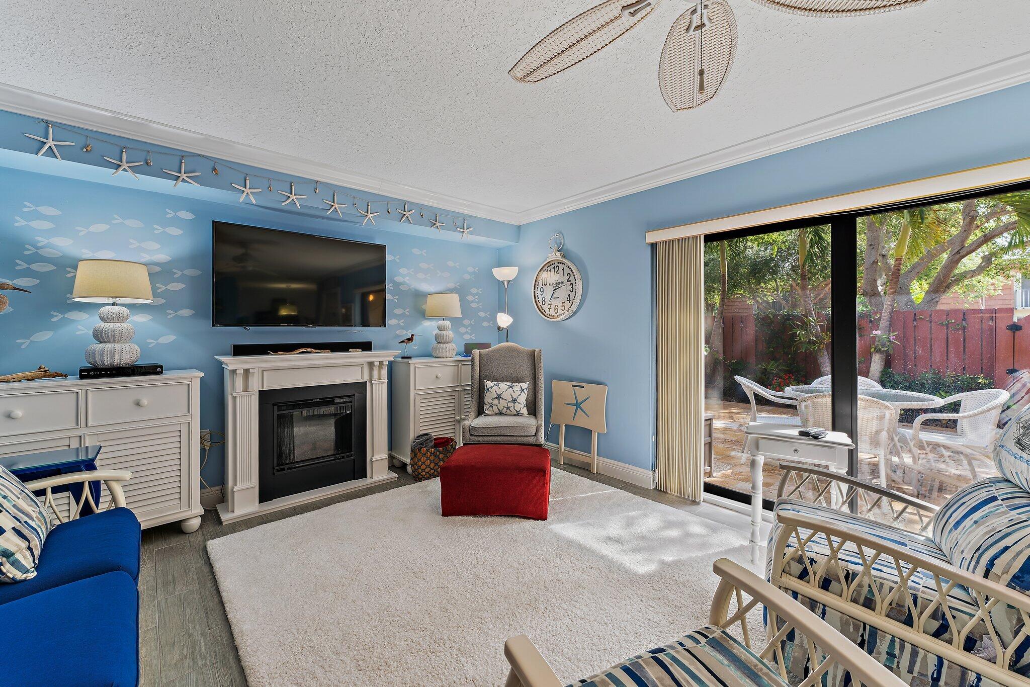 2403 24th Court Jupiter, FL 33477 - Photo 12 of 29 a living room with furniture a flat screen tv and a fireplace