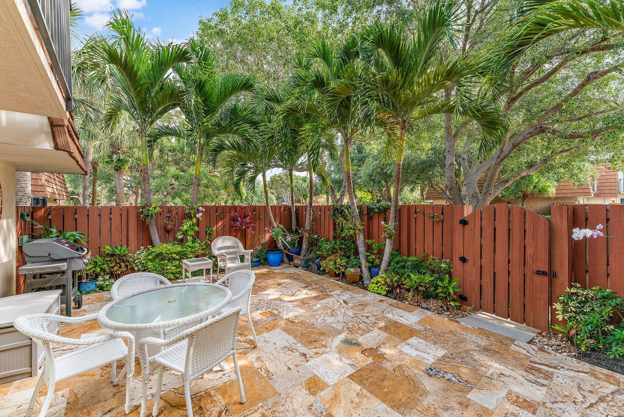 2403 24th Court Jupiter, FL 33477 - Photo 4 of 29 a backyard of a house with table and chairs plants and large tree