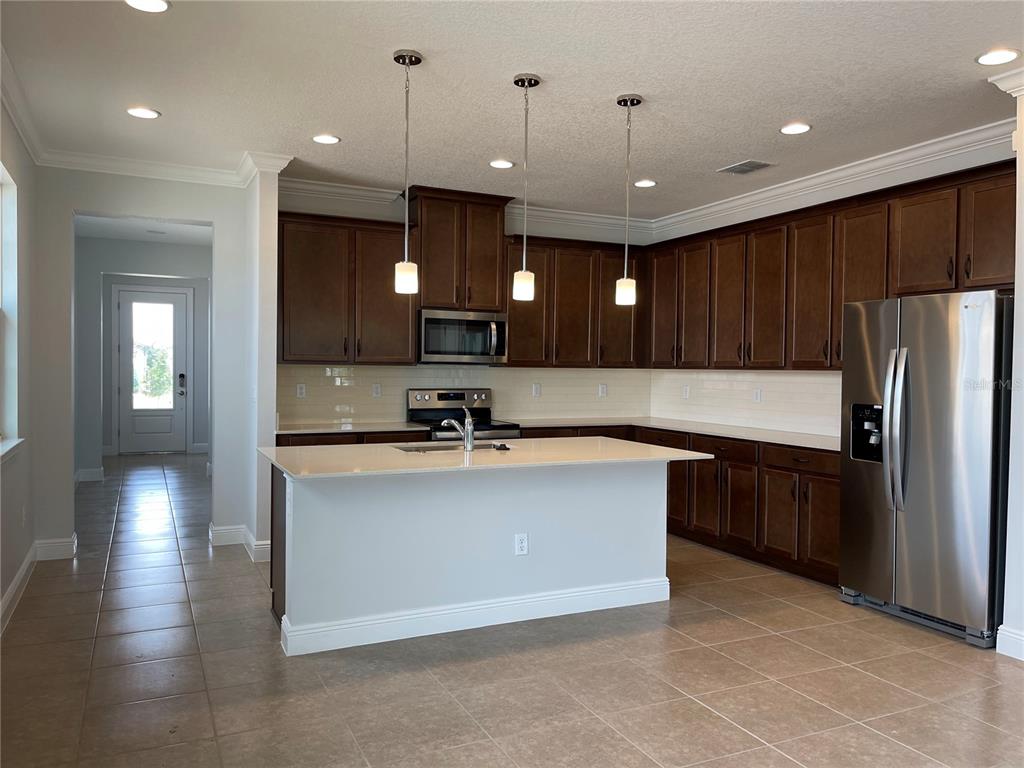3434 Sagebrush Street Harmony, FL 34773 - Photo 2 of 21 a large kitchen with kitchen island a sink stainless steel appliances and cabinets