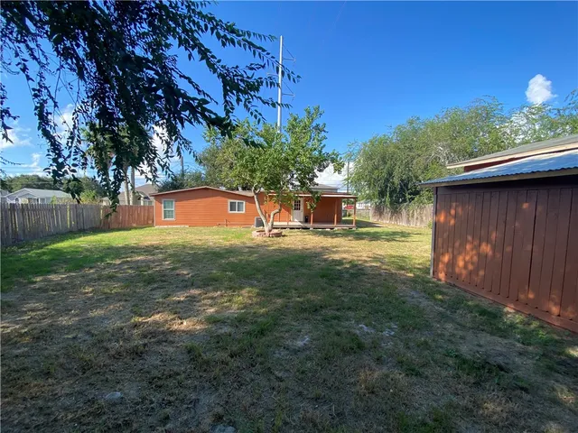 a backyard of a house with table and chairs under an umbrella