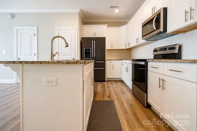 a kitchen with stainless steel appliances granite countertop a stove top oven a sink dishwasher and white refrigerator with wooden floor