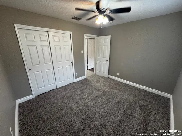 an empty room with windows and fan