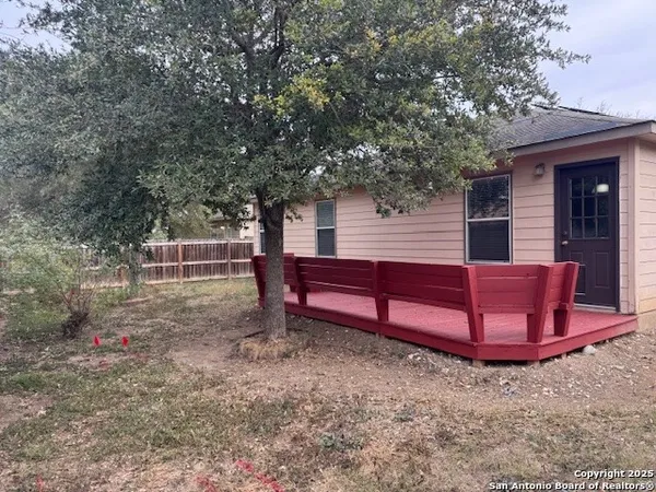 a backyard of a house with wooden fence and large trees