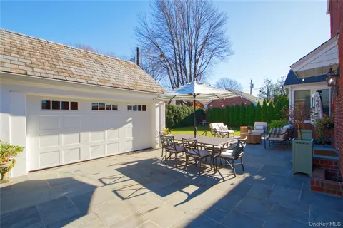 a view of a patio with couches table and chairs under an umbrella with a barbeque