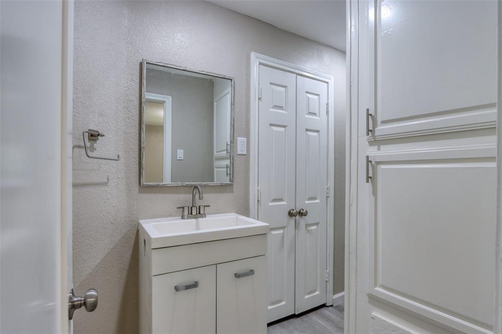 311 West McKinney Street Pilot Point, TX 76258 - Photo 13 of 33 The bathroom features a vanity with a white sink, a framed mirror, and white storage cabinetry