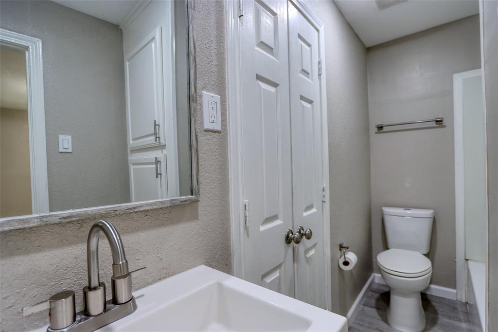 311 West McKinney Street Pilot Point, TX 76258 - Photo 14 of 33 The bathroom features a vanity with a white sink and chrome faucet, a large mirror, and a toilet