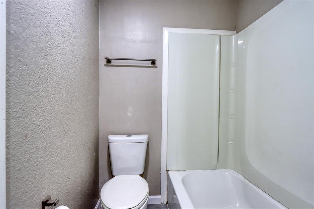 311 West McKinney Street Pilot Point, TX 76258 - Photo 15 of 33 The bathroom features a white toilet and a white bathtub with a shower surround