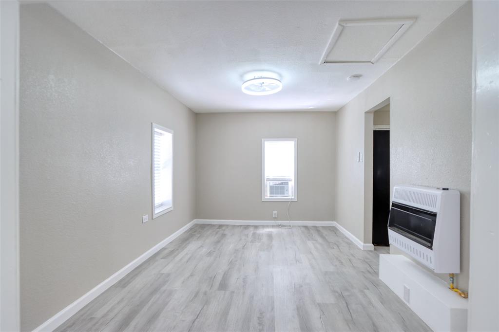 311 West McKinney Street Pilot Point, TX 76258 - Photo 16 of 33 Living area with light-colored walls, wood-style flooring, a ceiling-mounted light fixture, and two windows with blinds