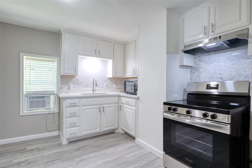 311 West McKinney Street Pilot Point, TX 76258 - Photo 19 of 33 The kitchen features white cabinetry, a stainless steel range, and light-colored flooring