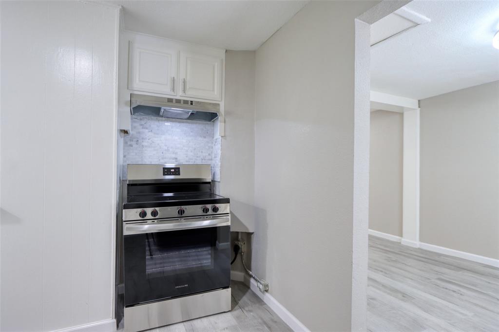 311 West McKinney Street Pilot Point, TX 76258 - Photo 21 of 33 Kitchen area featuring a stainless steel range with a ventilation hood, white cabinetry, and a tile backsplash