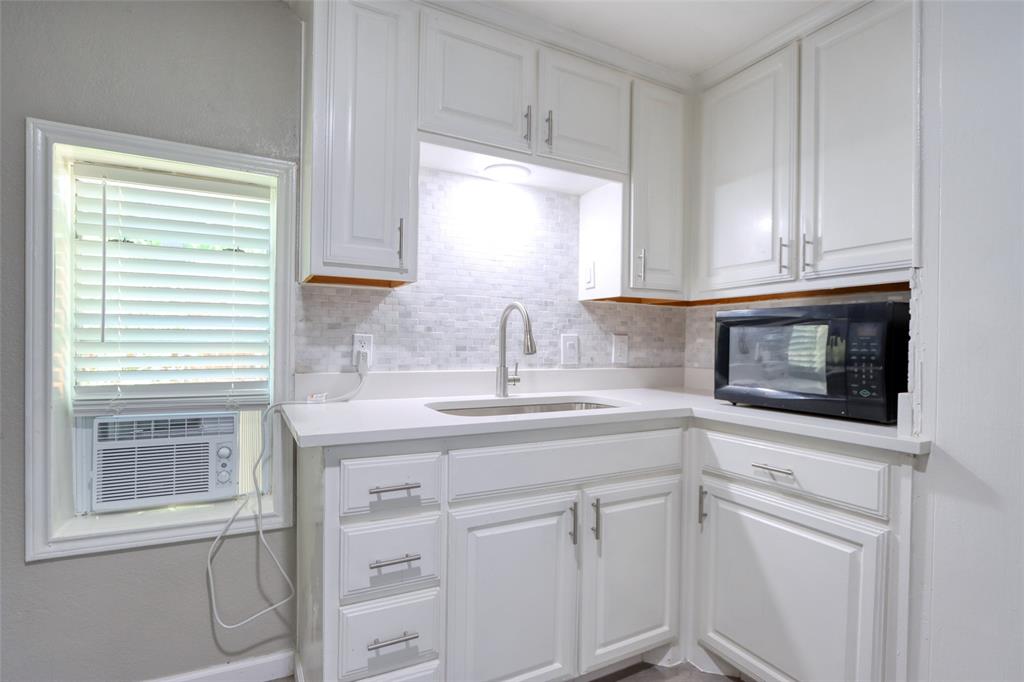 311 West McKinney Street Pilot Point, TX 76258 - Photo 22 of 33 The kitchen features white cabinetry, a sink with a modern faucet, and a light-colored countertop