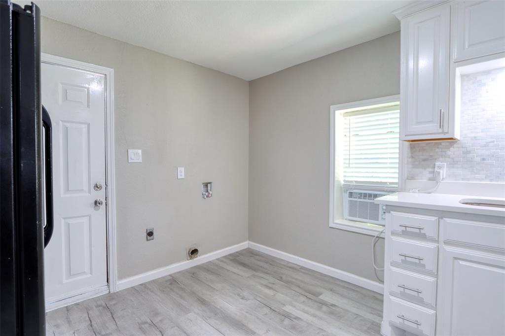 311 West McKinney Street Pilot Point, TX 76258 - Photo 23 of 33 Utility area with wood-look flooring, a white paneled door, and a window with blinds