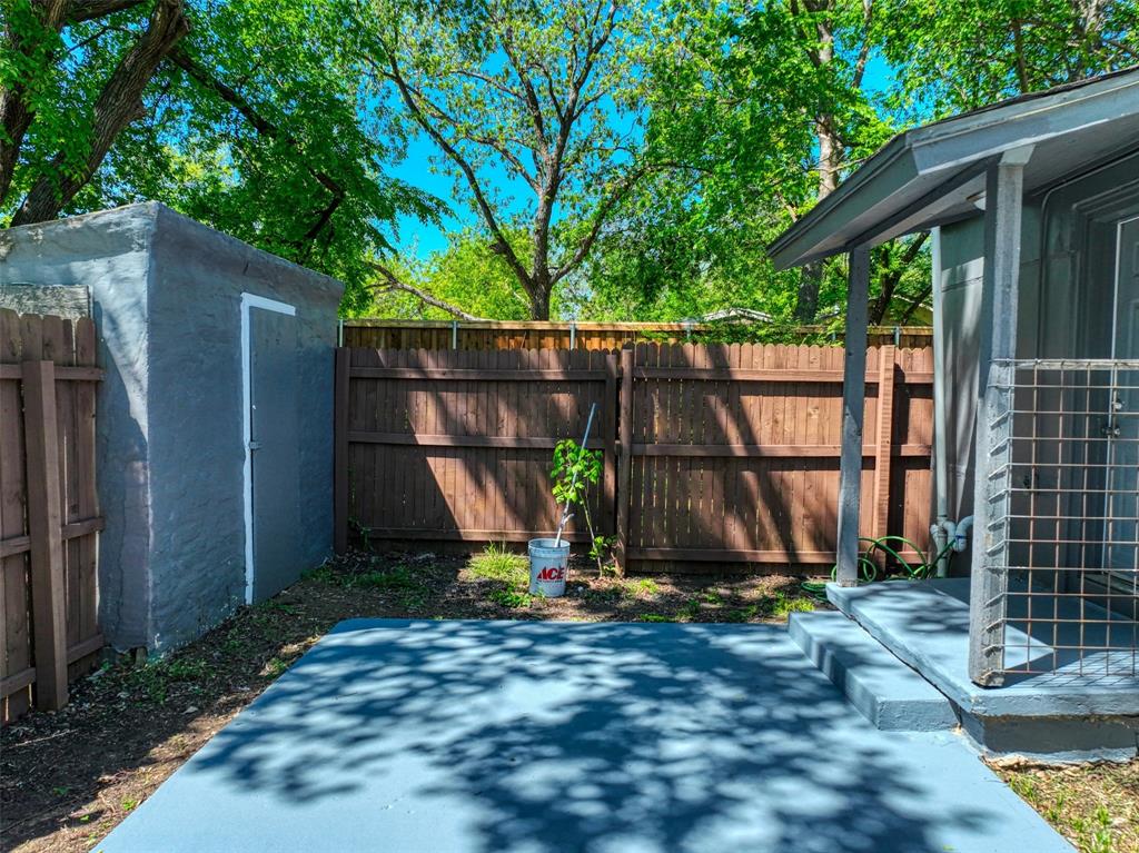 311 West McKinney Street Pilot Point, TX 76258 - Photo 27 of 33 The property features a concrete patio area, a concrete storage shed, and a wooden privacy fence