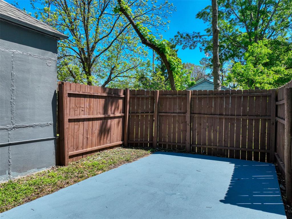 311 West McKinney Street Pilot Point, TX 76258 - Photo 28 of 33 Enclosed outdoor space featuring a blue-painted concrete patio, a wooden fence, and a patch of grass