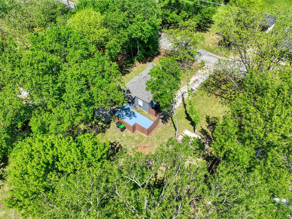 311 West McKinney Street Pilot Point, TX 76258 - Photo 32 of 33 Aerial view showcasing the property's privacy, surrounded by mature trees, with a visible pool and a nearby road