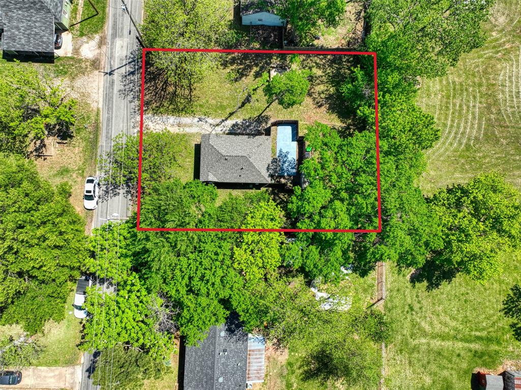 311 West McKinney Street Pilot Point, TX 76258 - Photo 33 of 33 The property offers a sizable lot with mature trees, a private driveway, and a residential structure featuring a gray shingled roof