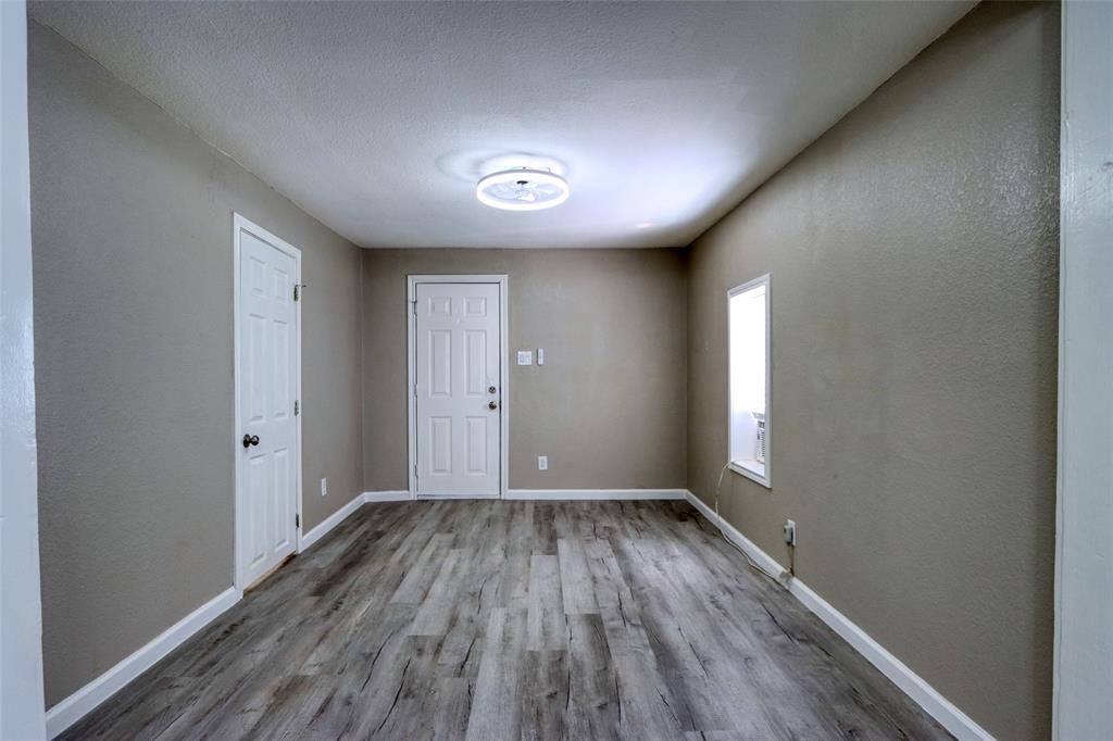 311 West McKinney Street Pilot Point, TX 76258 - Photo 5 of 33 Spacious room featuring wood-look flooring, neutral wall tones, and a contemporary ceiling light fixture