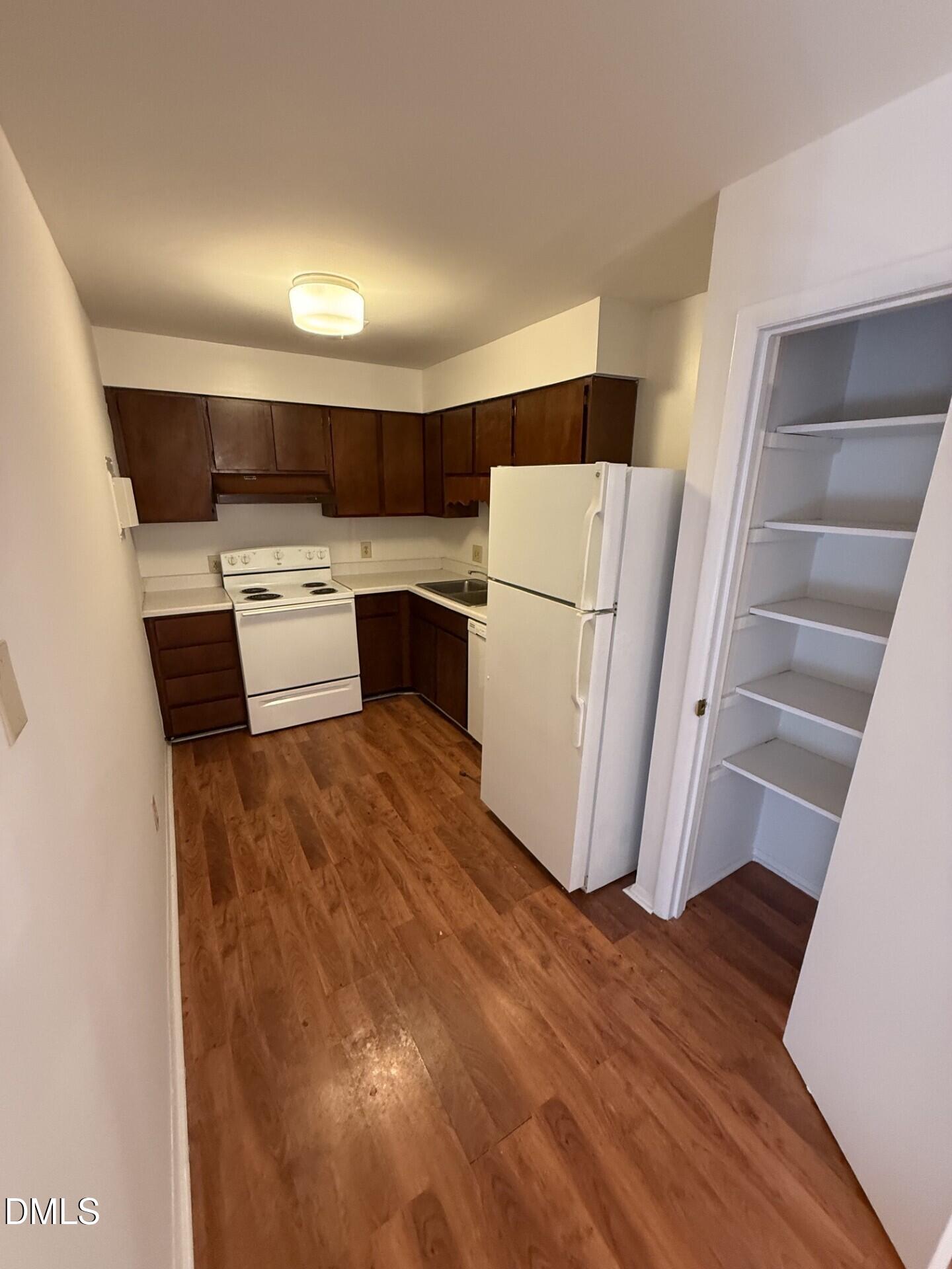 1299 Schaub Drive, Unit D Raleigh, NC 27606 - Photo 6 of 16 a kitchen with a refrigerator a stove top oven and wooden floor