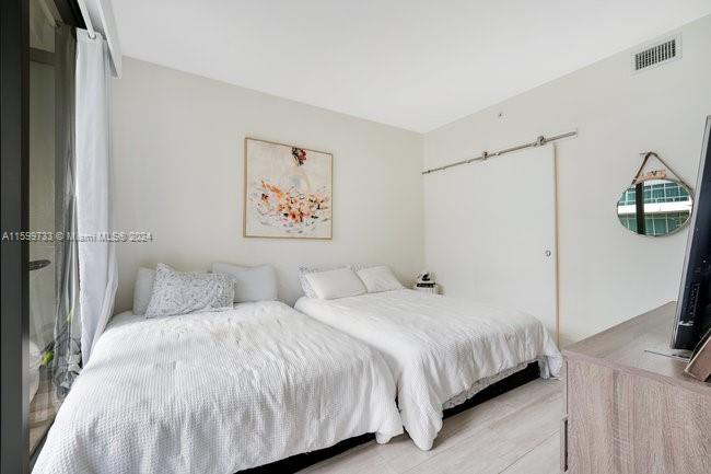 121 Northeast 34th Street, Unit L303 Miami, FL 33137 - Photo 14 of 31 a bedroom with a bed and a flat screen tv