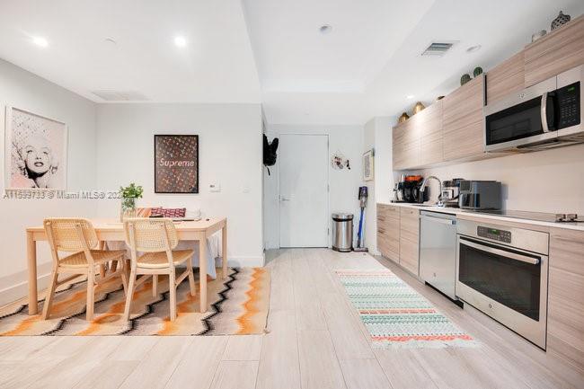 121 Northeast 34th Street, Unit L303 Miami, FL 33137 - Photo 10 of 31 a kitchen with stainless steel appliances kitchen island granite countertop a stove a sink and a microwave