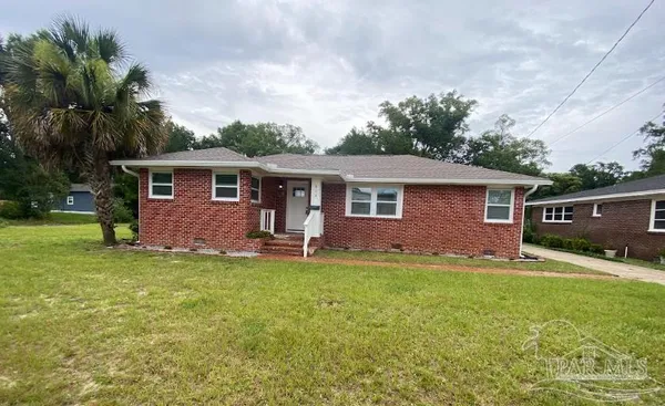 a front view of house with yard and trees in the background