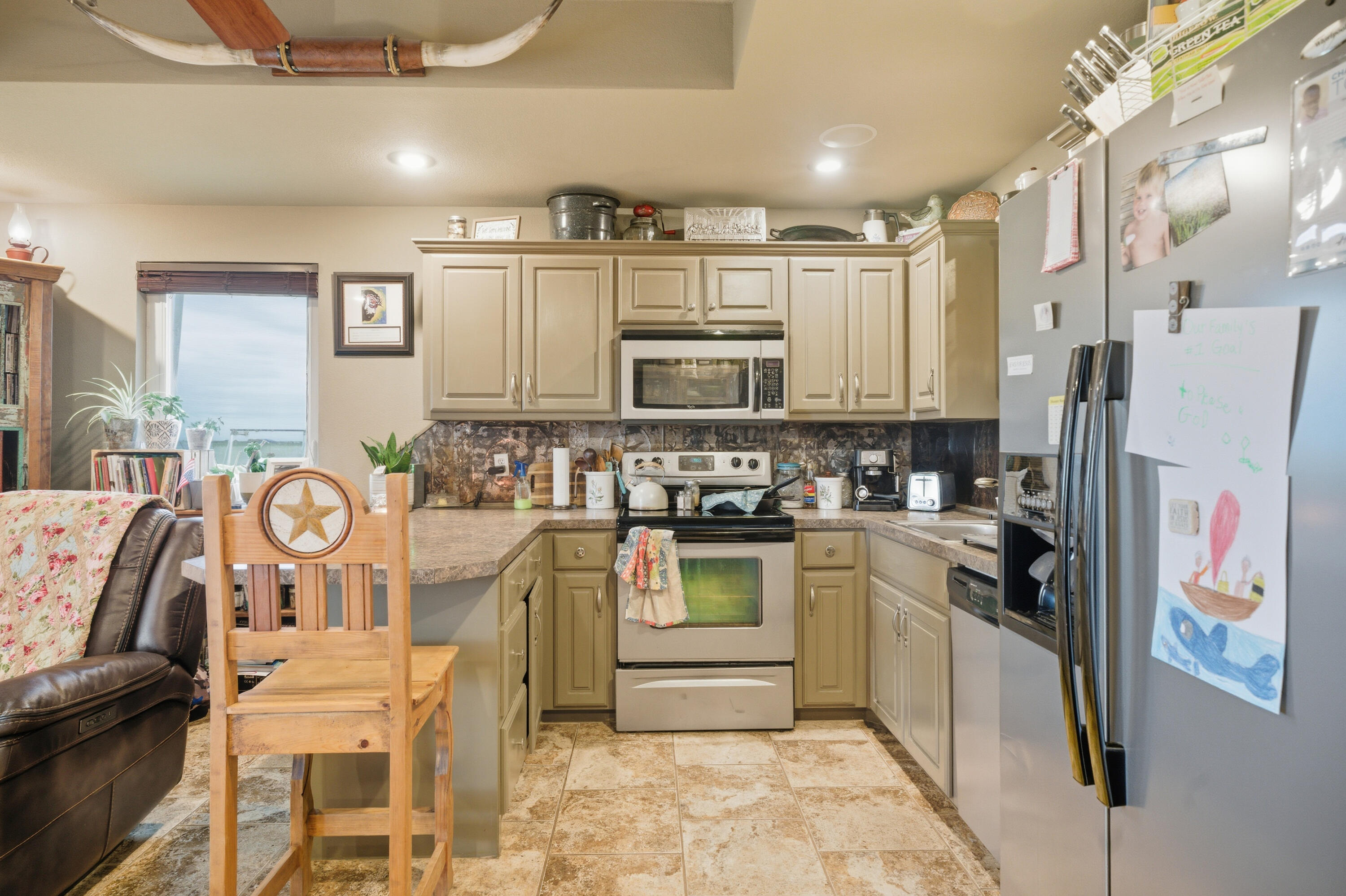 672 Cr M Road New Home, TX 79381 - Photo 19 of 30 a kitchen with stainless steel appliances kitchen island granite countertop a refrigerator and microwave