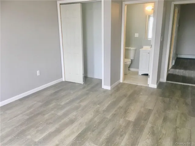 an empty room with wooden floor and a bathroom