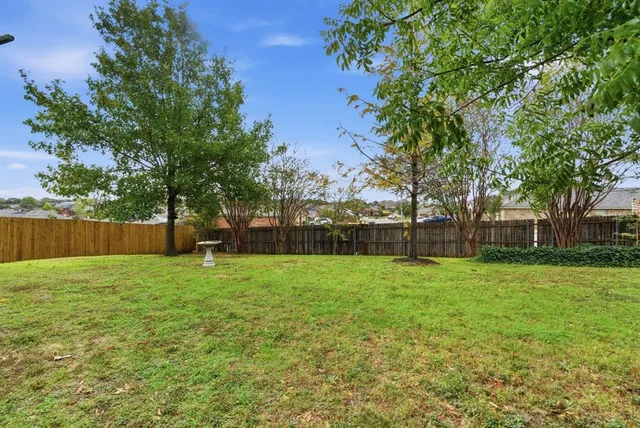 a view of a tiny house with a small yard and wooden fence