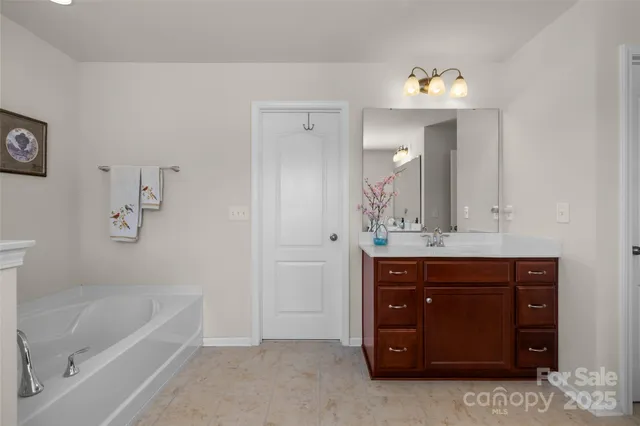 a spacious bathroom with a tub sink and mirror