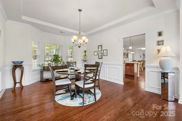 a dining room with furniture a chandelier and wooden floor