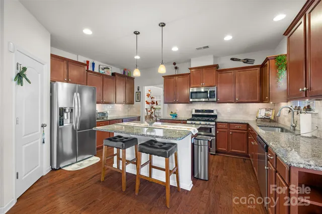 a kitchen with stainless steel appliances granite countertop a refrigerator a stove top oven a sink dishwasher and white cabinets