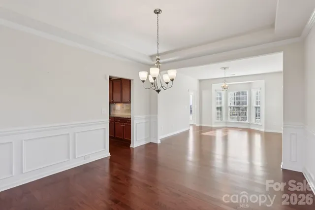 an empty room with wooden floor fireplace and windows