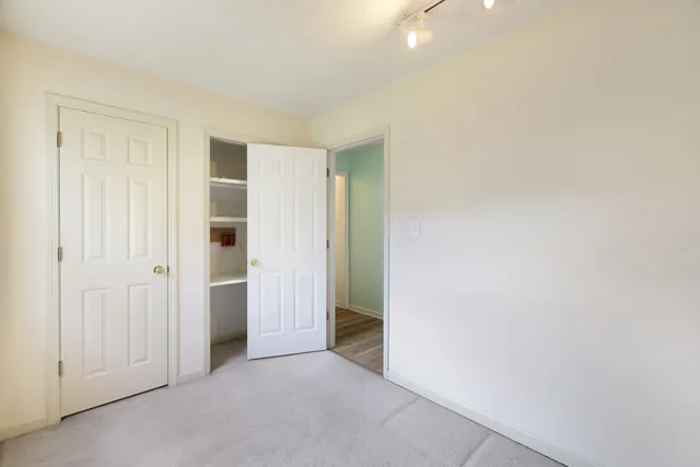 an empty room with windows and chandelier fan