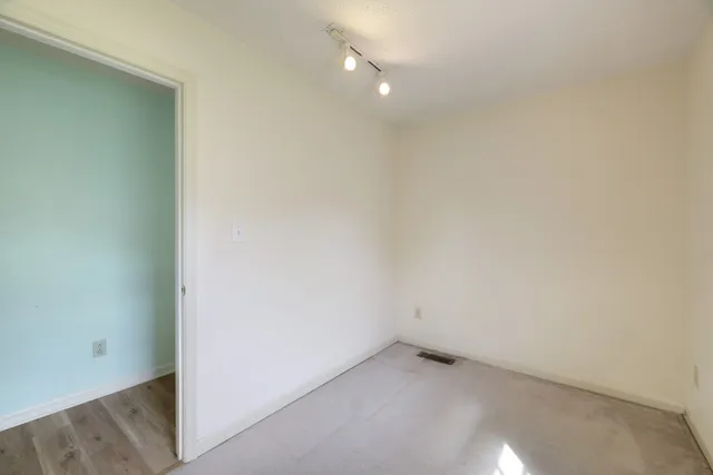 an empty room with windows and fan