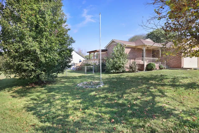 a view of a house with a big yard and large trees