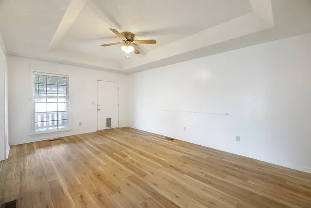 a view of an empty room with wooden floor and a window