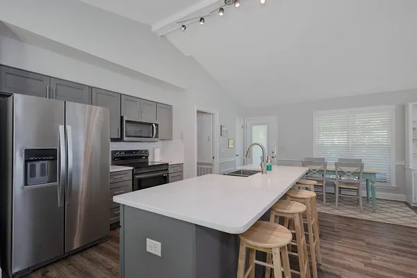 a kitchen with kitchen island a refrigerator stove microwave and dining table