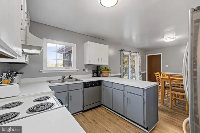 a kitchen with stainless steel appliances a sink a stove a refrigerator cabinets and a window