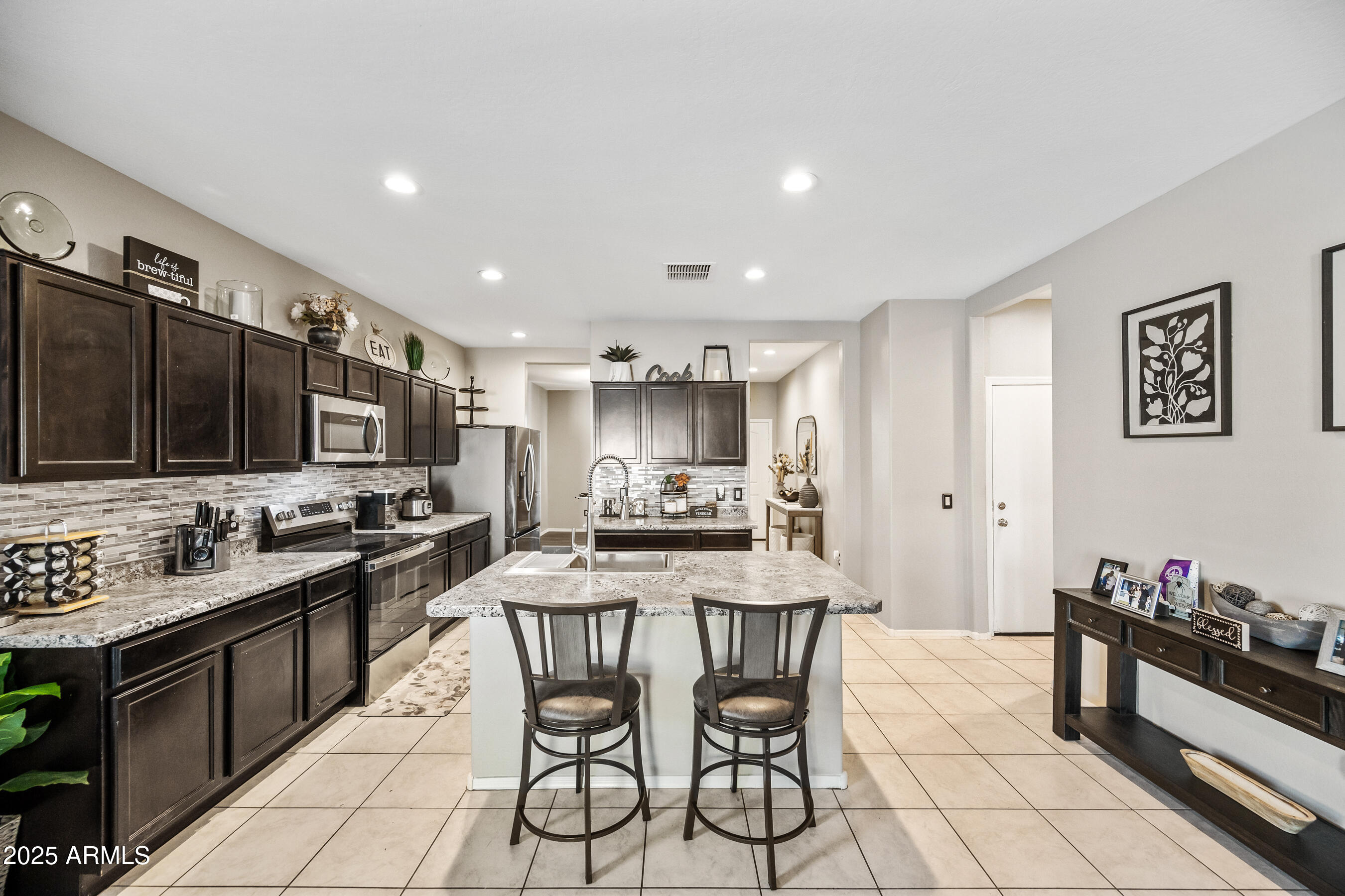 25626 West Coles Road Buckeye, AZ 85326 - Photo 8 of 31 a kitchen with stainless steel appliances kitchen island granite countertop a sink and cabinets