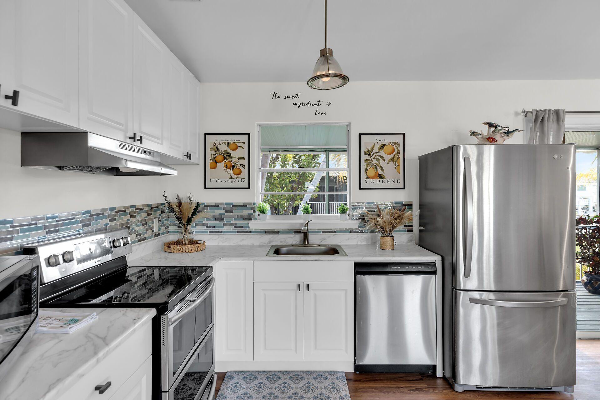 878 La Paloma Road Key Largo, FL 33037 - Photo 12 of 38 a kitchen with stainless steel appliances granite countertop a refrigerator a stove a sink and a microwave