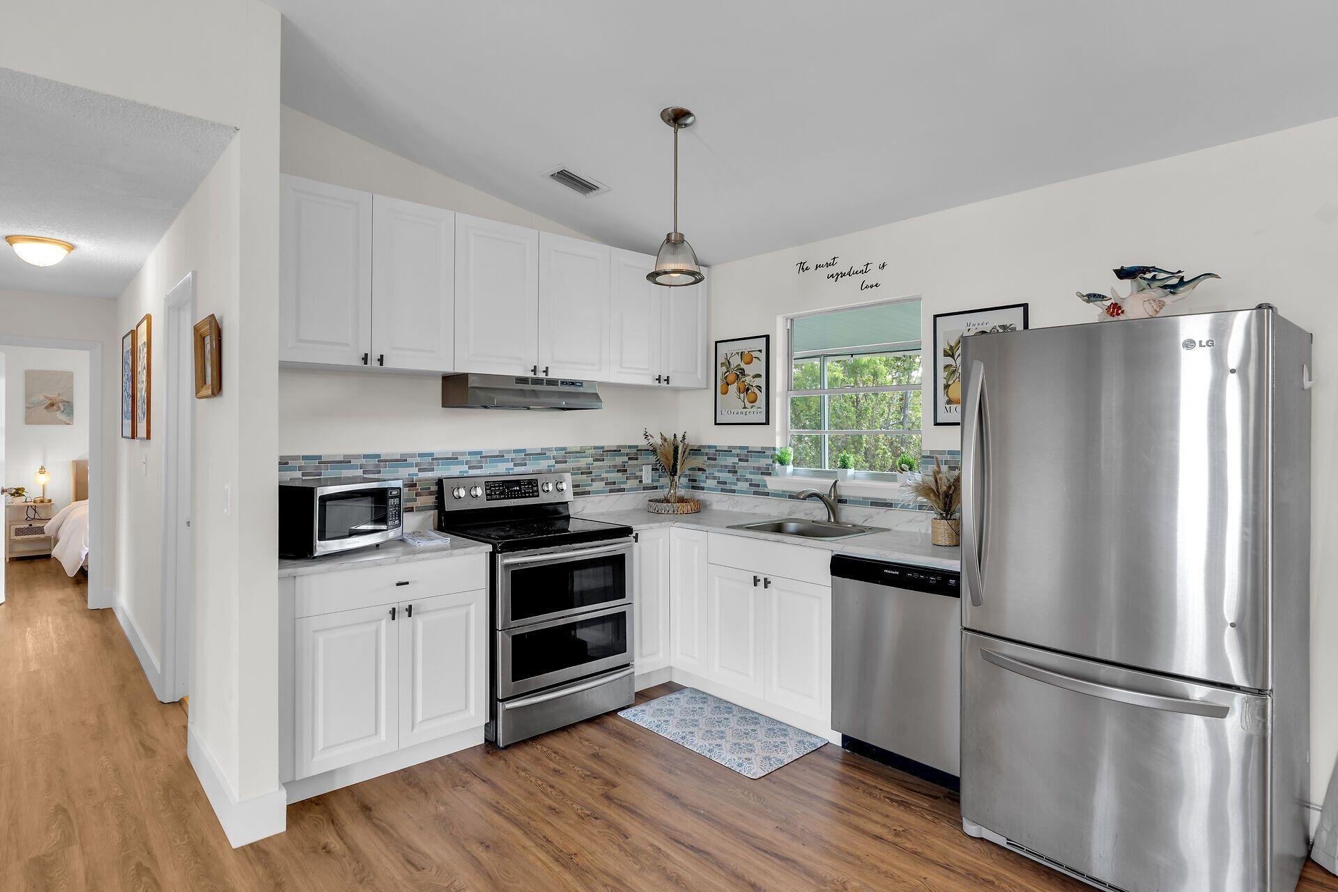 878 La Paloma Road Key Largo, FL 33037 - Photo 13 of 38 a kitchen with stainless steel appliances a refrigerator sink and wooden floor