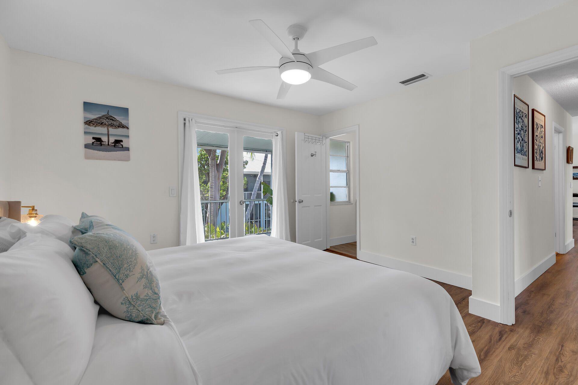 878 La Paloma Road Key Largo, FL 33037 - Photo 16 of 38 a bedroom with a large bed and a chandelier