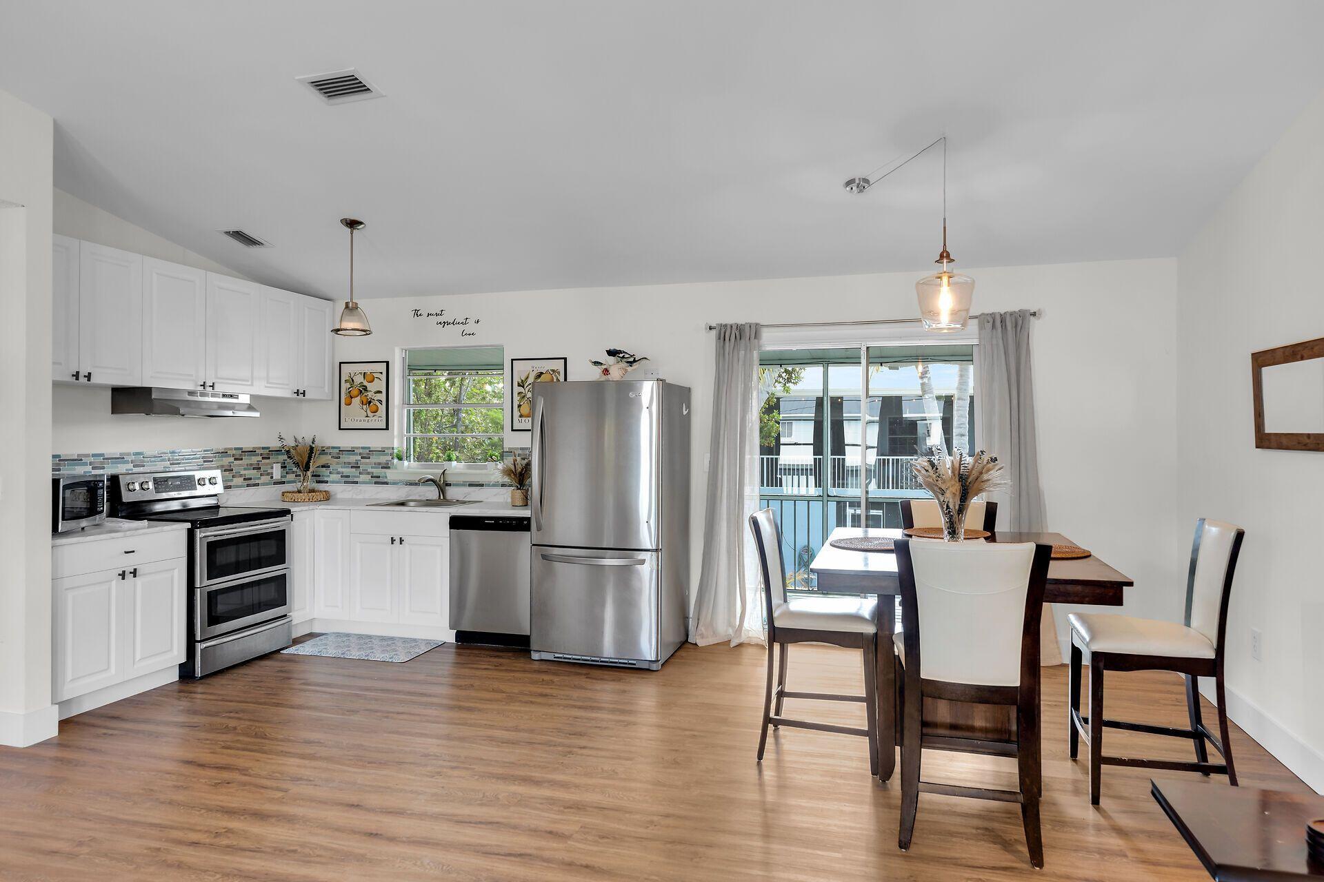 878 La Paloma Road Key Largo, FL 33037 - Photo 10 of 38 a kitchen with stainless steel appliances granite countertop a stove top oven a refrigerator a dining table and chairs with wooden floor