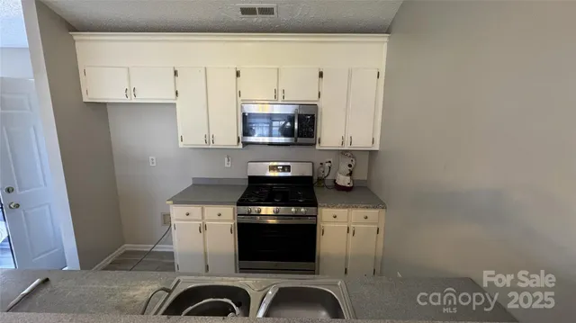 a kitchen with granite countertop white cabinets and black appliances