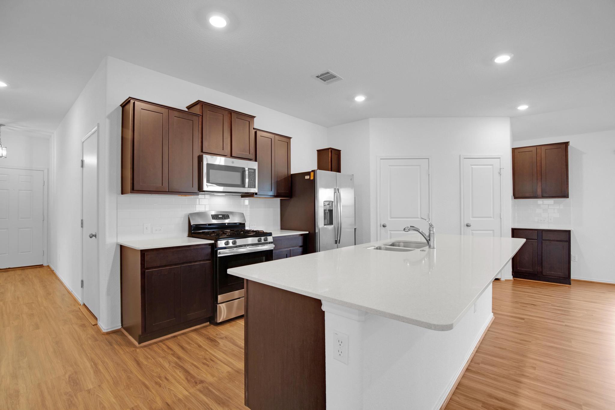 21409 Resource Road Pflugerville, TX 78660 - Photo 4 of 23 Kitchen featuring tasteful backsplash, stainless steel appliances, an island with sink, light wood-type flooring, and recessed lighting